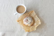 Cinnamon roll with cream on paper and cup of coffee with milk