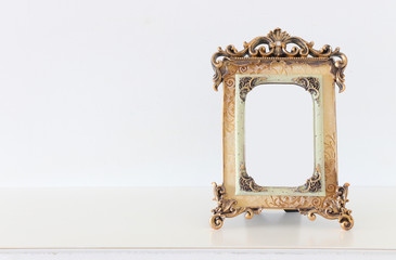 Wall Mural - Image of gold tone baroque vintage empty photo frame over wooden table. For mockup, can be used for photography montage