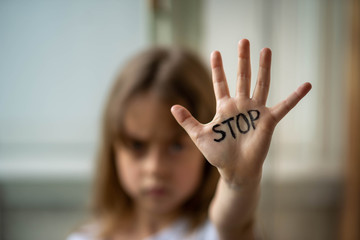 the child makes a stop gesture with his hand. stop domestic and child abuse.