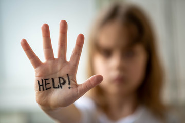 little girl asks for help, help written on hand. domestic and child abuse.