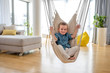 © Drpixel - Adorable little smiling boy enjoying on indoor swing in bright modern living room