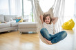 © Drpixel - Adorable smiling girl enjoying on indoor swing in bright modern living room
