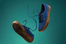 Close Up View Of Levitation Blue Sneakers Shoes With  Flying Laces Over Green Background With Copy Space For Text. 
