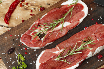 Wall Mural - Raw meat steaks with herbs on wooden board