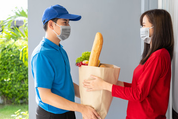 Wall Mural - Food Delivery man wearing mask give fruit and vegetable shopping supermarket to receiver woman customer front house, express grocery service when crisis coronavirus, covid19 new normal lifestyle.