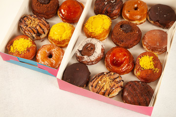 Assorted gourmet doughnuts with filling and delicious toppings freshly baked in a box for delivery take out