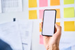 © baranq - Closeup of man holding smartphone at startup office