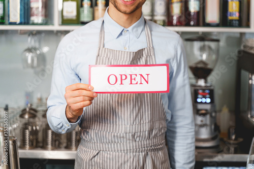 Fotografía Young man in apron holding open sign