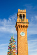 Top of Murano clock tower Torre dell'Orologio and Colorful christmas tree made of Murano Glass on Campo Santo Stefano square, Murano islands, Veneto Region, Northern Italy, Vertical view