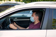 © OneWellStudio - A man driving a car in a medical face mask during coronavirus outbreak, a taxi driver in a mask, protection from the virus. Quarantine, covid-19.