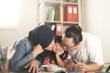 Wall Mural - Asian muslim parents drawing with their daughter, mother and father teaching baby girl, happy family concept