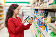 © _KUBE_ - A young Caucasian woman scans the qr code on a package of cereals. Concept of modern technologies and shopping