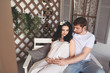 © Алина Троева - Pregnancy and people concept - happy man hugging his beautiful pregnant wife at home. Future parents waiting unborn baby. Love, relationship, birth, happy family concept - young lovely married couple