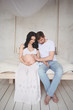 © Алина Троева - Pregnancy and people concept - happy man hugging his beautiful pregnant wife at home. Future parents waiting unborn baby. Love, relationship, birth, happy family concept - young lovely married couple