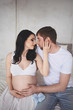 © Алина Троева - Pregnancy and people concept - happy man hugging his beautiful pregnant wife at home. Future parents waiting unborn baby. Love, relationship, birth, happy family concept - young lovely married couple