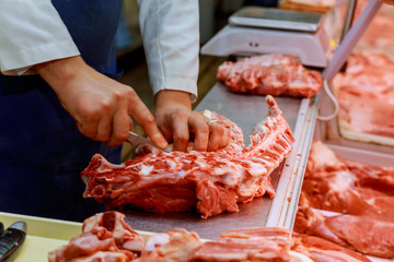 Wall Mural - Hands of a butcher cutting slices of raw meat