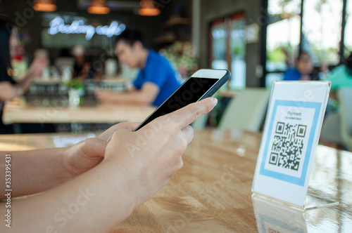 Women\'s hands are using  the phone to scan the qr code to select food menu. Scan to get discounts or pay for food. The concept of using a phone to transfer money or paying money online without cash.