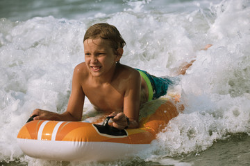 Kid riding on the foam wave on the bodyboard