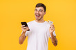 © Drobot Dean - Photo of delighted young man holding credit card and cellphone