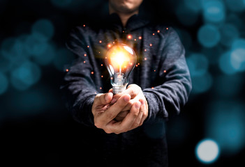 Wall Mural - Businessman holding glowing lightbulb with orange light . Creative new business idea concept.