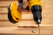 © SockaGPhoto - a male hand holding a  yellow battery operated drill with a screwdriver bit in a construction environment