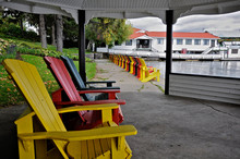 Multi-colored Muskoka Chairs Inside The Patio Gazebo And  Other At The Lakefront Of The Tourist Resort