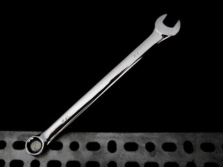 the open end of a combination box and open end wrench on a bolt head on a black background