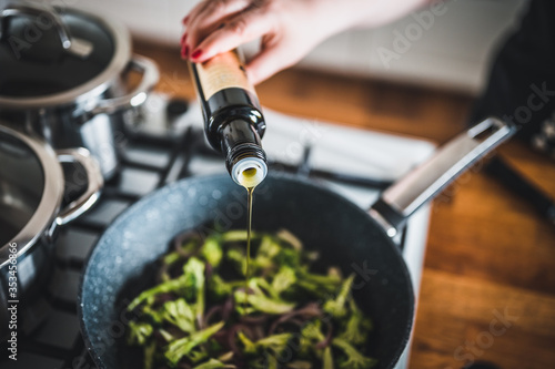 Cuadros en Lienzo Woman's hand pours olive oil on grilled vegetables in a cast iron grilling pan