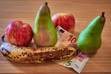 Wall Mural - Fruit lying together with European banknotes on a wooden background.