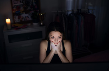 Wall Mural - Scared and worried young girl with laptop sitting indoors, internet abuse concept.