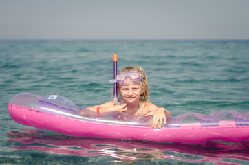 Wall Mural - cute girl with glasses for diving on inflatable pink airbed and sunbathing