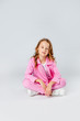 © Julie Boro - girl in a pink tracksuit and sneakers sits on a light gray background