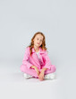 © Julie Boro - girl in a pink tracksuit and sneakers sits on a light gray background