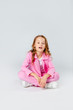 © Julie Boro - girl in a pink tracksuit and sneakers sits on a light gray background
