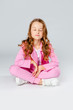 © Julie Boro - girl in a pink tracksuit and sneakers sits on a light gray background