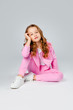 © Julie Boro - girl in a pink tracksuit and sneakers sits on a light gray background