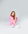 © Julie Boro - girl in a pink tracksuit and sneakers sits on a light gray background