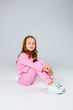 © Julie Boro - girl in a pink tracksuit and sneakers sits on a light gray background