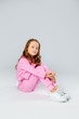 © Julie Boro - girl in a pink tracksuit and sneakers sits on a light gray background