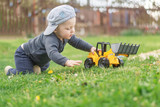 Fototapeta Dinusie - A small child with a toy in the garden.