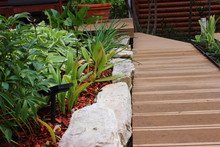 Design Of A Modern Garden. Walkways Made Of Wood-plastic Composite Boards. A Border Made Of Natural Stone. Gardening And Decoration Of Backyard.