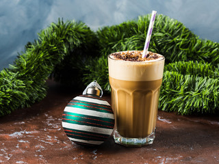 Frappe milk shake coffee in tall glass on blue and brown background. Christmas new year holiday drink