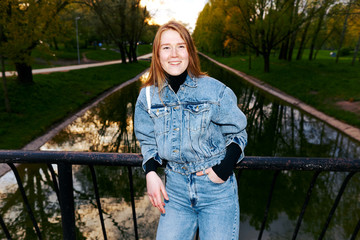 Flash photo of a beautiful redhead girl in 80s jeans in a park near the water