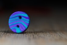 Closeup Shot Of A Blue Button Put On A Wooden Surface