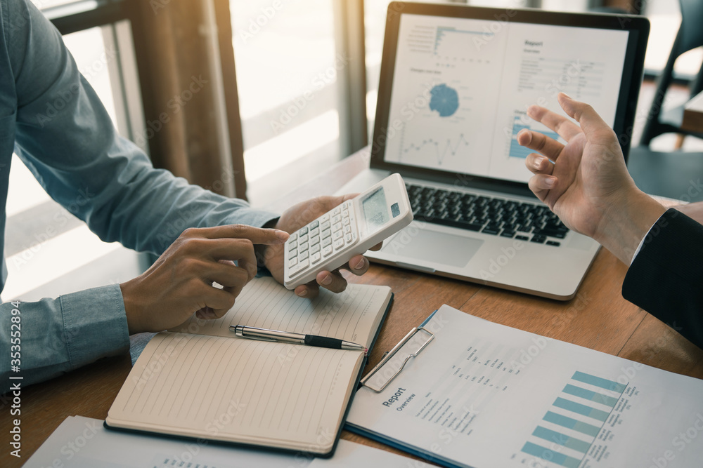 Two business partnership coworkers analysis strategy with discussing a financial planning graph and company budget during a budget meeting in office room.