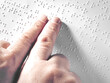 © Andy Shell - Hands of a blind person reading some braille text touching the relief. Horizontal
