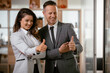 © JustLife - Businessman and businesswoman showing thumbs up. Colleagues working together in office.