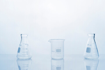Wall Mural - clear glass beaker and flask in clean white blue research science laboratory background