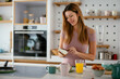 © JustLife - Beautiful woman eating breakfast in the kitchen. Young woman enjoy at home.