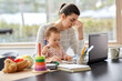 © Syda Productions - remote job, multi-tasking and family concept - tired mother with baby working at home office
